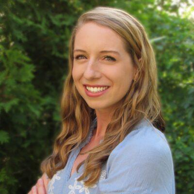 A color photo of a woman smiling for a photo outside