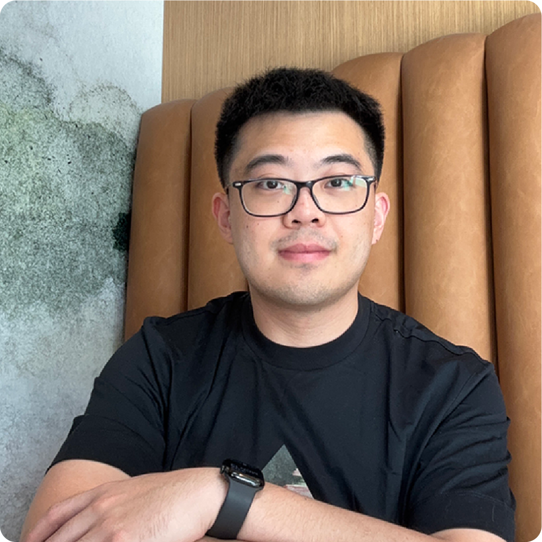 A color photo of a man with glasses sitting in a restaurant booth.