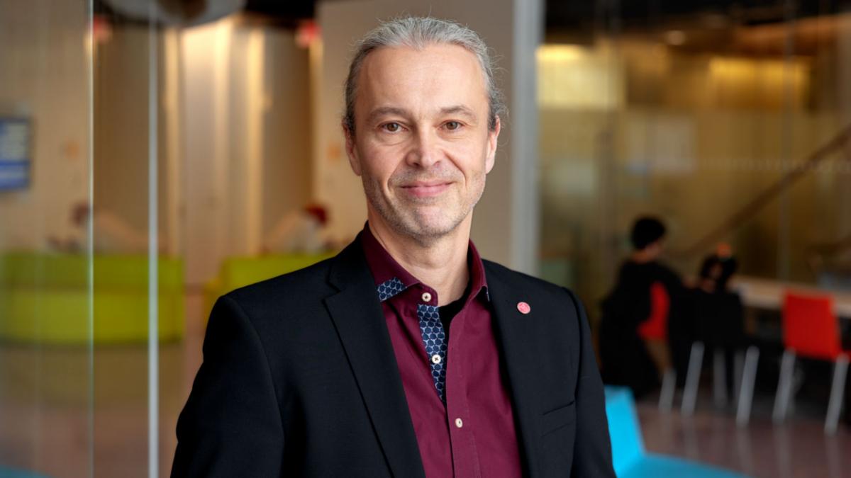 A color photo of a man smiling for a photo.