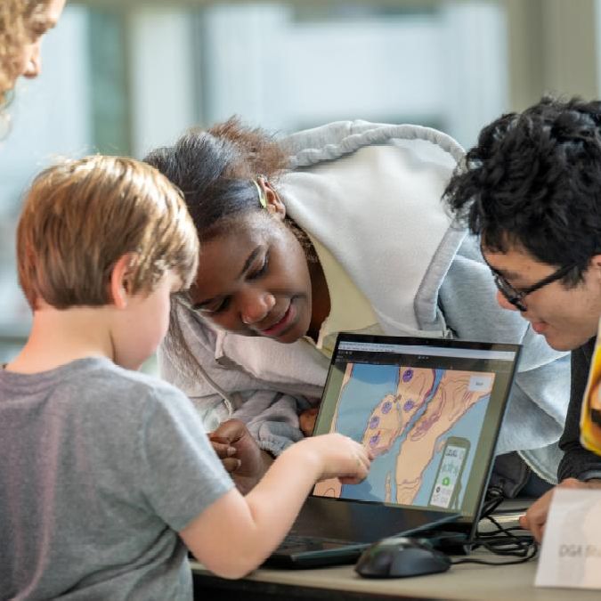 A color photo showing a child playing a game on a computer at BOOM 2025