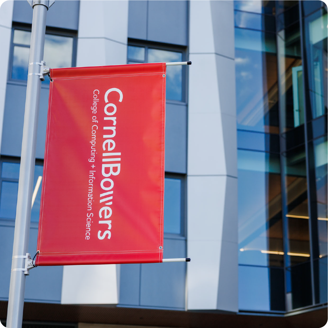 A color photo showing a red banner with the Cornell Bowers logo on it.