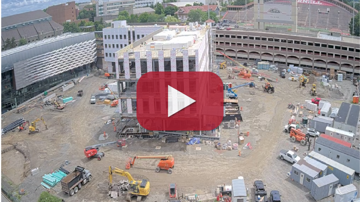 A color photo showing construction being started on a new building with a red 'play' icon