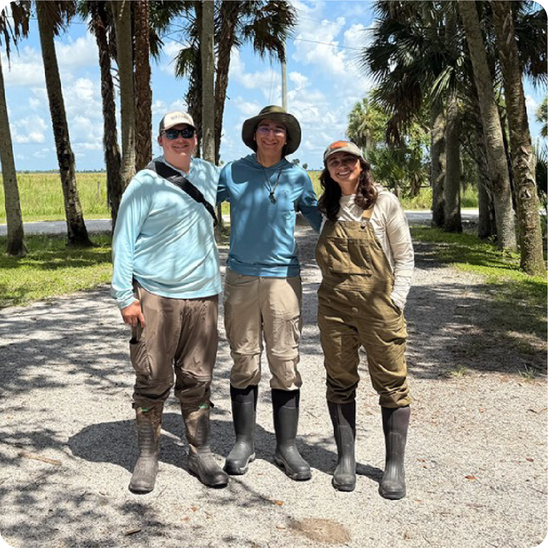 A color photo that shows 3 people standing outside for a photo.
