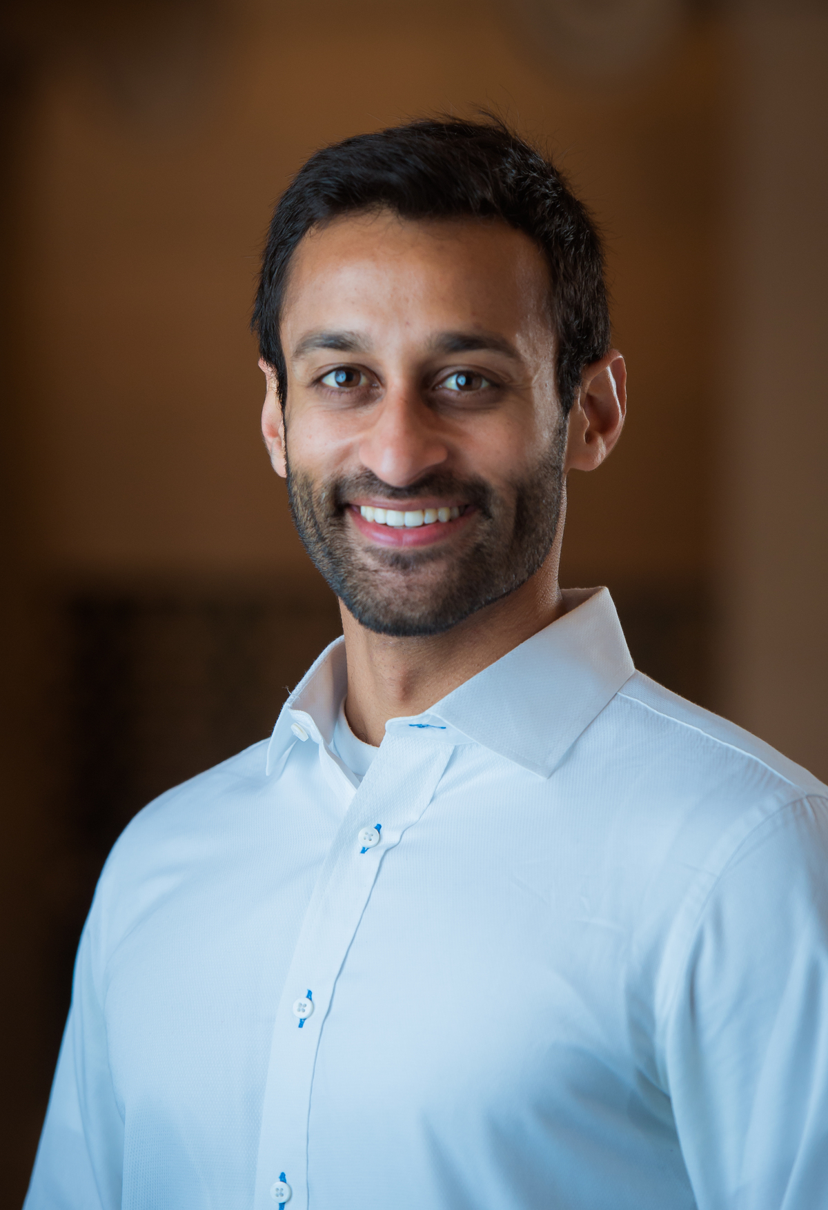 Man in white dress shirt and beard smiling at camera