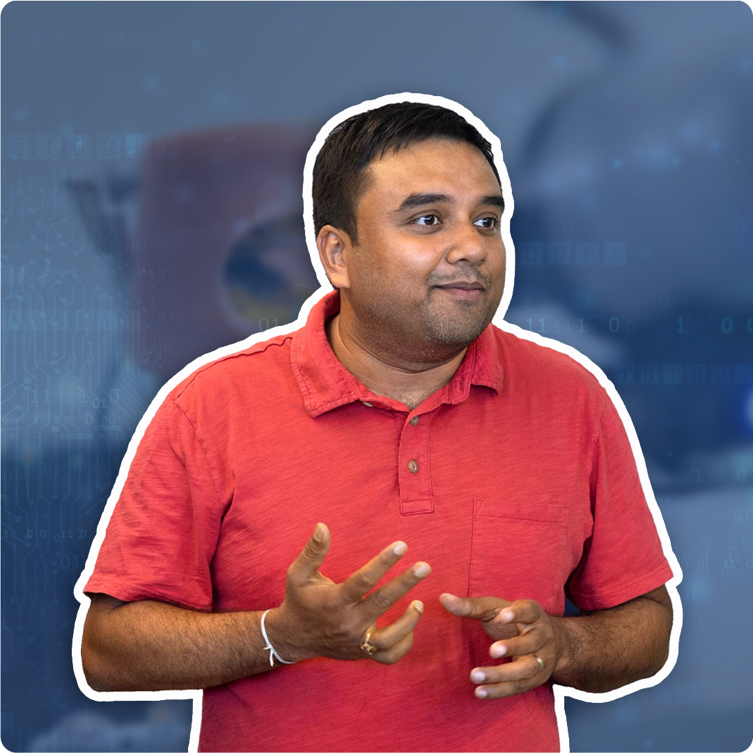 A color photo of a man in a red shirt with a blurred blue background