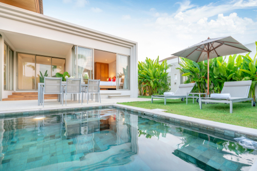 home or house Exterior design showing tropical pool villa with greenery garden_ sun bed_ umbrella_ pool towels