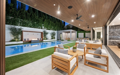 A lush green patio boasts an expansive pool and inviting seating area_ New Construction Home in Tarzana_ California