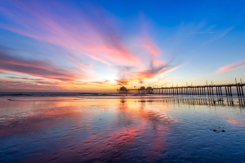 Surreal scenery as the sun sets below the horizon along Huntington Beach_ casting a beautiful glow and peaceful landscape.  