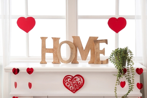 Mantelpiece with decorative word HOME and hearts for Valentine s Day celebration near window