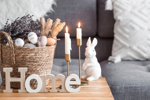 Provence. A wicker basket with Easter eggs_ lavender_ candles and white rabbits in the interior of the living room on a wooden table. The concept of home comfort in the bright holiday of Easter 2022.