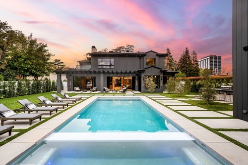 A luxurious modern house with a swimming pool in the backyard_ surrounded by greenery and a beautiful sunset sky.