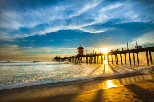 Beautiful Sunset and Clouds flowing through the Huntington Beach pier and onto the beach 