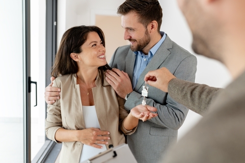 A young_ beautiful_ and cheerful couple_  a man and his pregnant wife_ talking with a real-estate agent visiting apartment for sale or for rent. Future parents buying an apartment. Real estate concept