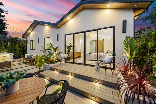Modern patio with stylish furniture_ plants_ and warm lighting during sunset_ showcasing contemporary outdoor living.