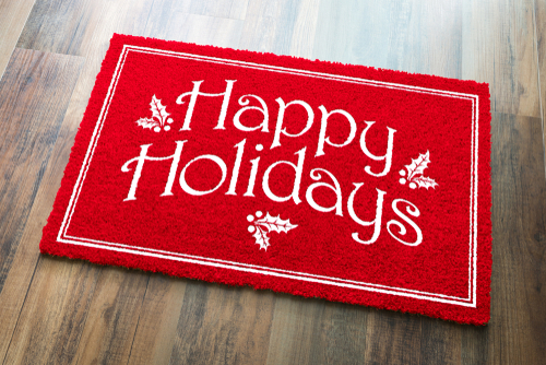 Happy Holidays Christmas Red Welcome Mat On Wood Floor Background.