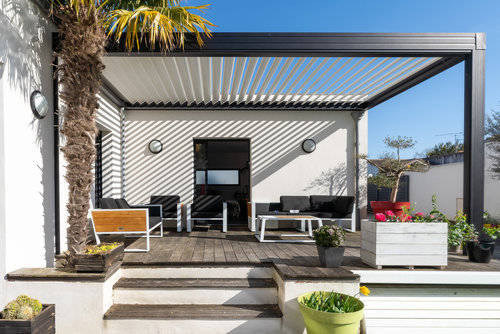 Trendy outdoor patio pergola shade structure_ awning and patio roof_ garden lounge_ chairs_ metal grill surrounded by landscaping