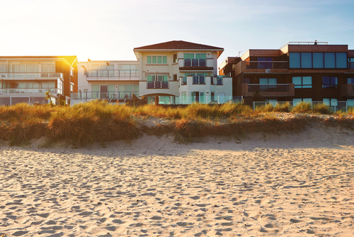 Front view of house on the beach and a setting sun_ real estate with space for text