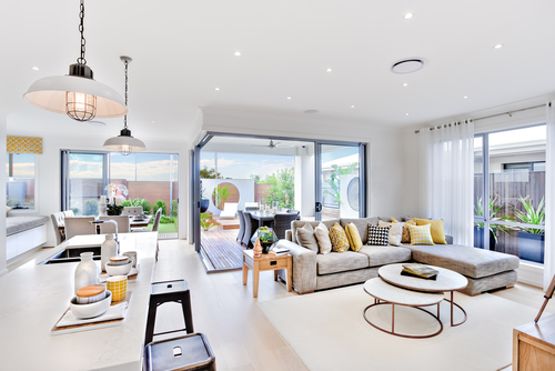 Modern kitchen area attached to the living room beside a patio and dinner area near to outside entrance_ there are hanging lamps
