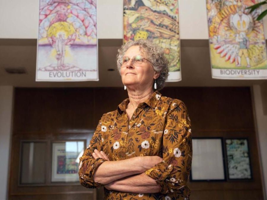 Woman with crossed arms standing in front of iillustrated biology posters
