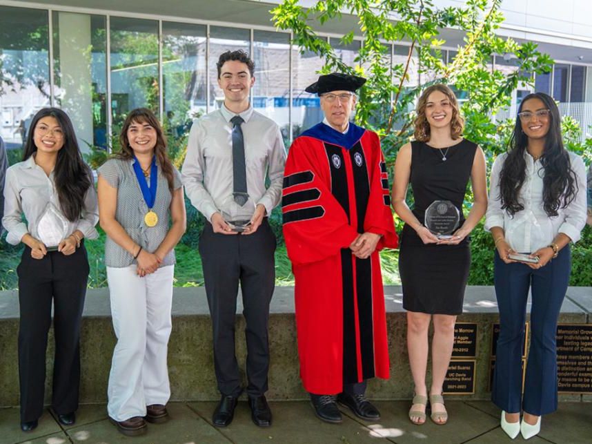 A group of students with their awards standing by the dean in regalia