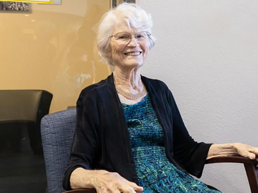 Elderly woman sitting in a chair wearing a black sweater