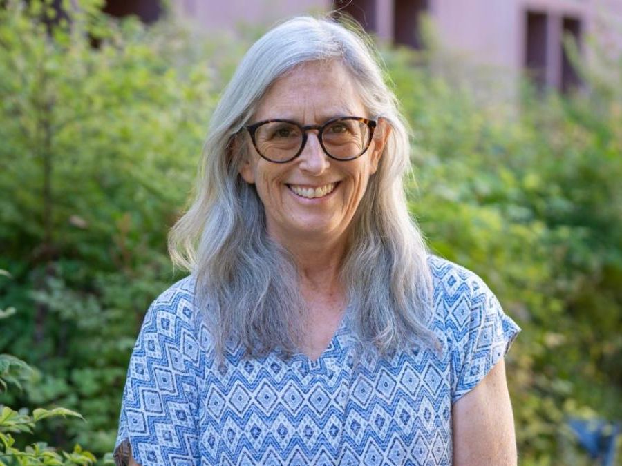A woman in glasses with grey hair standing outside