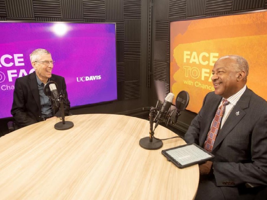 Mark Winey and Chancellor Gary S. May sit at a round table with microphones, smiling during a recorded conversation in a studio.