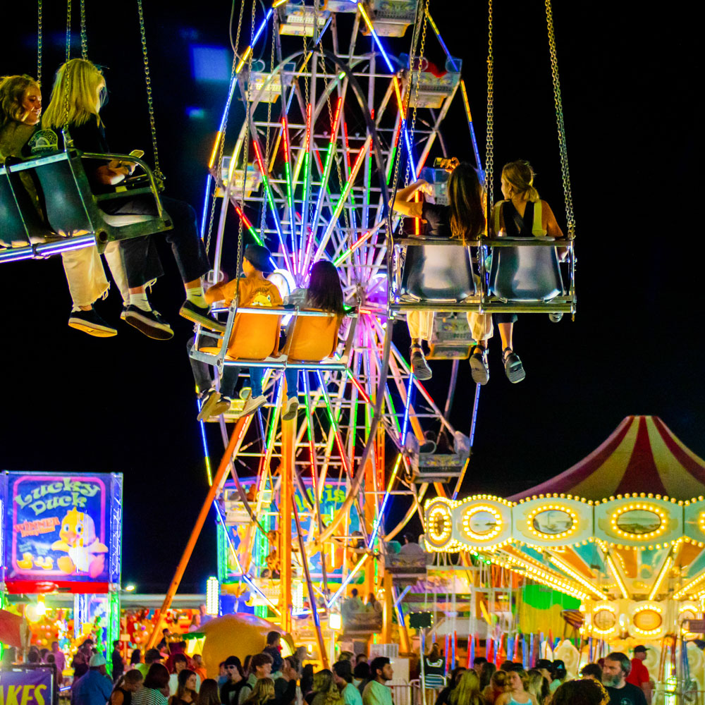 carnival lights at night, people riding rides