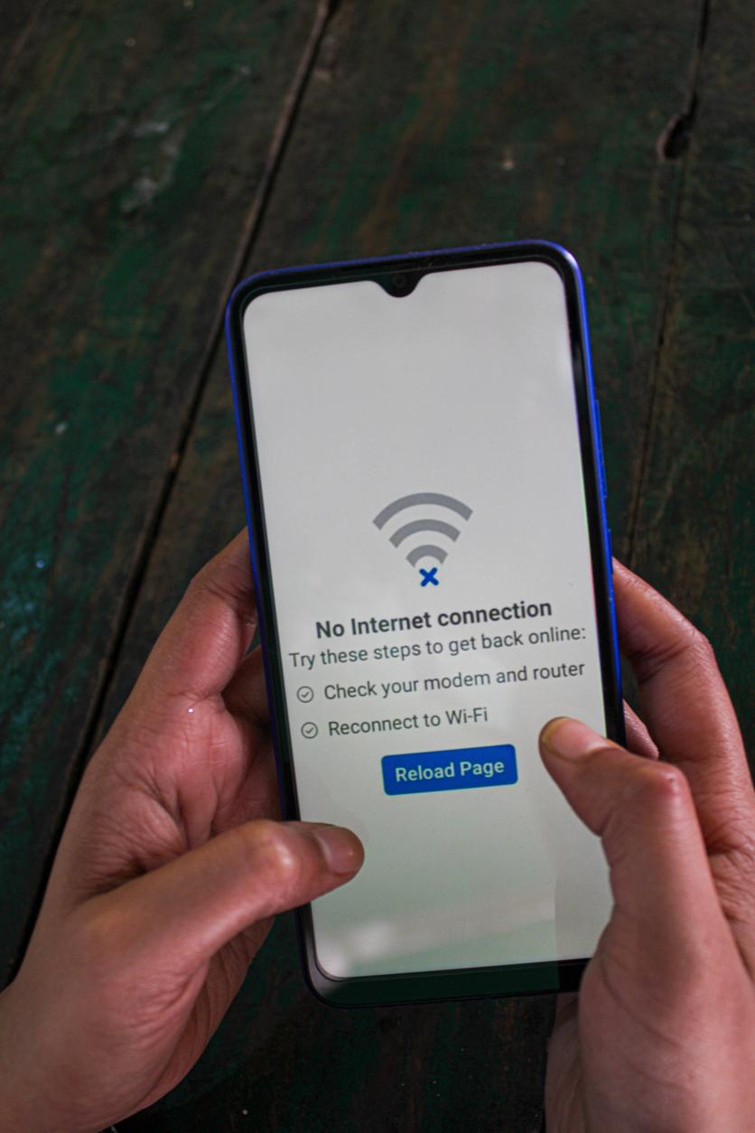 person holding smart phone that shows no internet available