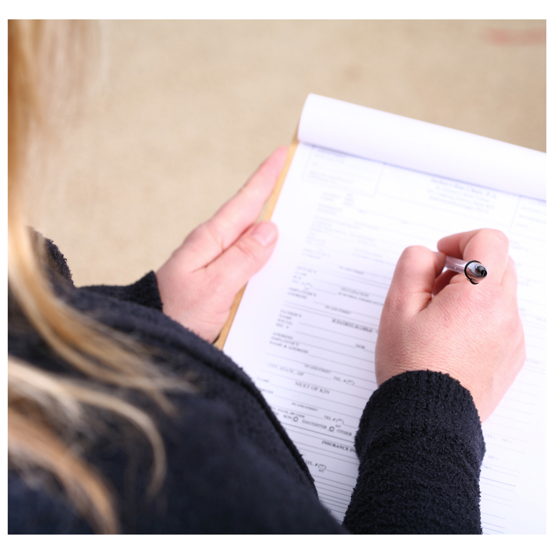 A side view picture of a women making notes on a piece of paper.