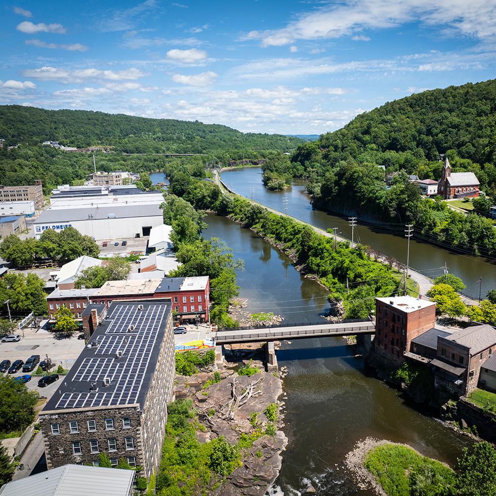 Aerial view of the Erie Canal going through Little Falls with stone mills, a bridge, and other buildings in view