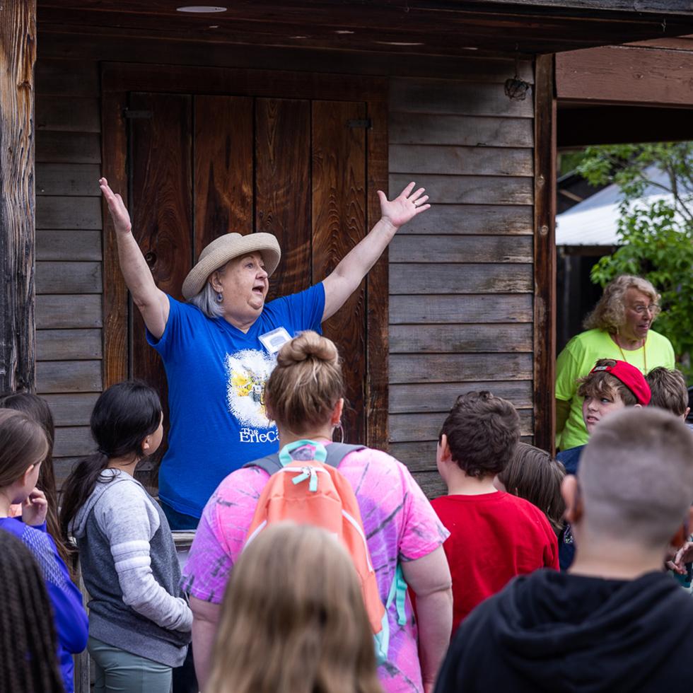 A woman puts her hands in the air to welcome students on a field trip to Camillus Erie Canal Park