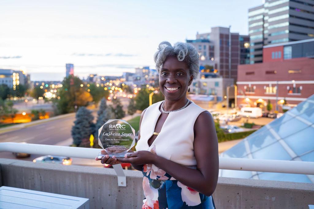 Person smiles and holds award