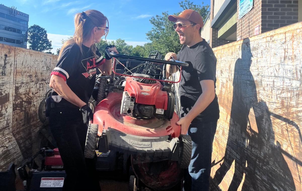 2 people load mower into bin