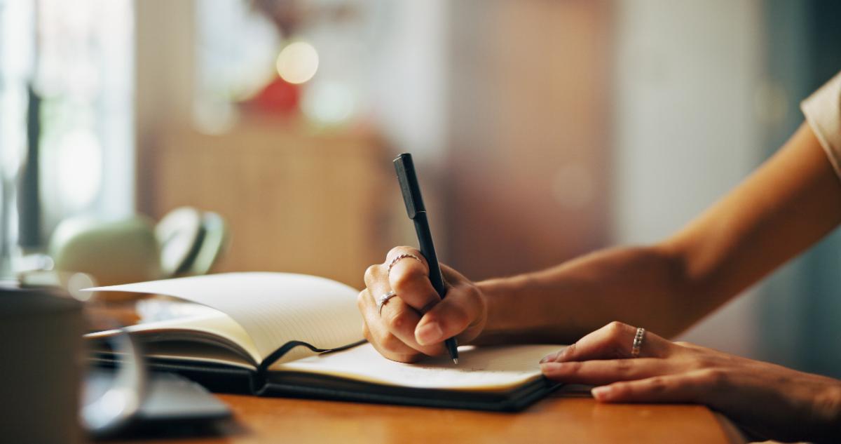 Home person and hands with notebook for writing schedule or daily reflection for wellness. Closeup writer and student with journal for assessment reminder to do list or thoughts for mental health
