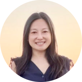 Photo of a woman smiling wearing a blue dress with long hair and a cream background