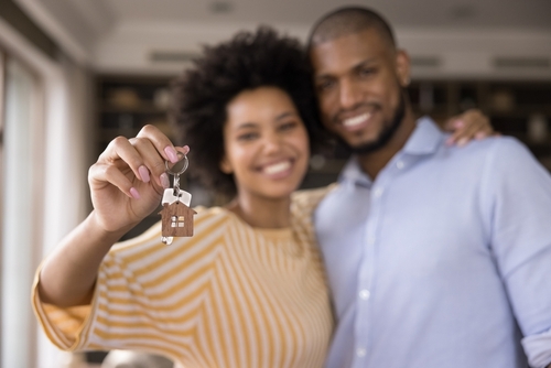 Happy Black millennial couple showing keys_ smiling at camera_ hugging. Husband and wife_ new homeowners_ tenants excited with house buying_ real estate property purchase_ renting apartment. Close up