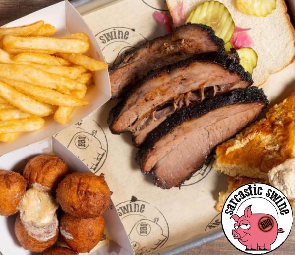 Sliced brisket with a side of french fries hush puppies and cornbread