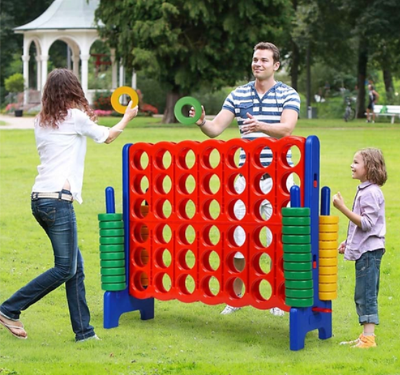 A mom dad and child playing a giant version of 4 in a Line outside