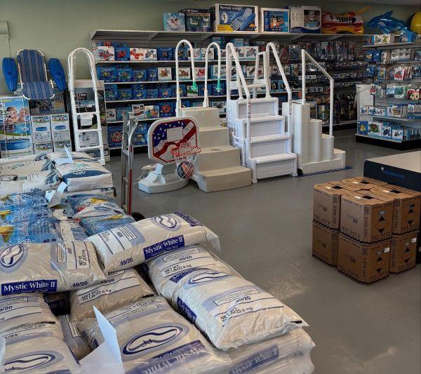 Image of pool store with shelves of pool floats ladders and stacks of pool chemicals