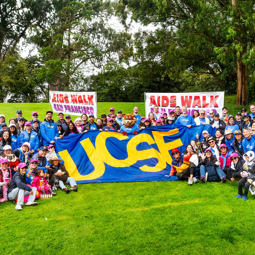 UCSF AIDS Walk team gathered in the park with a large UCSF sign