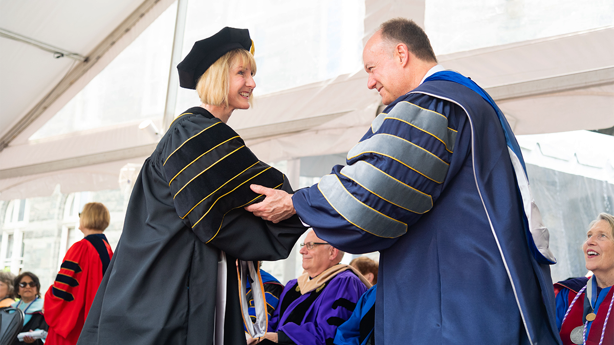 President DeGioia shaking hands with a doctoral student