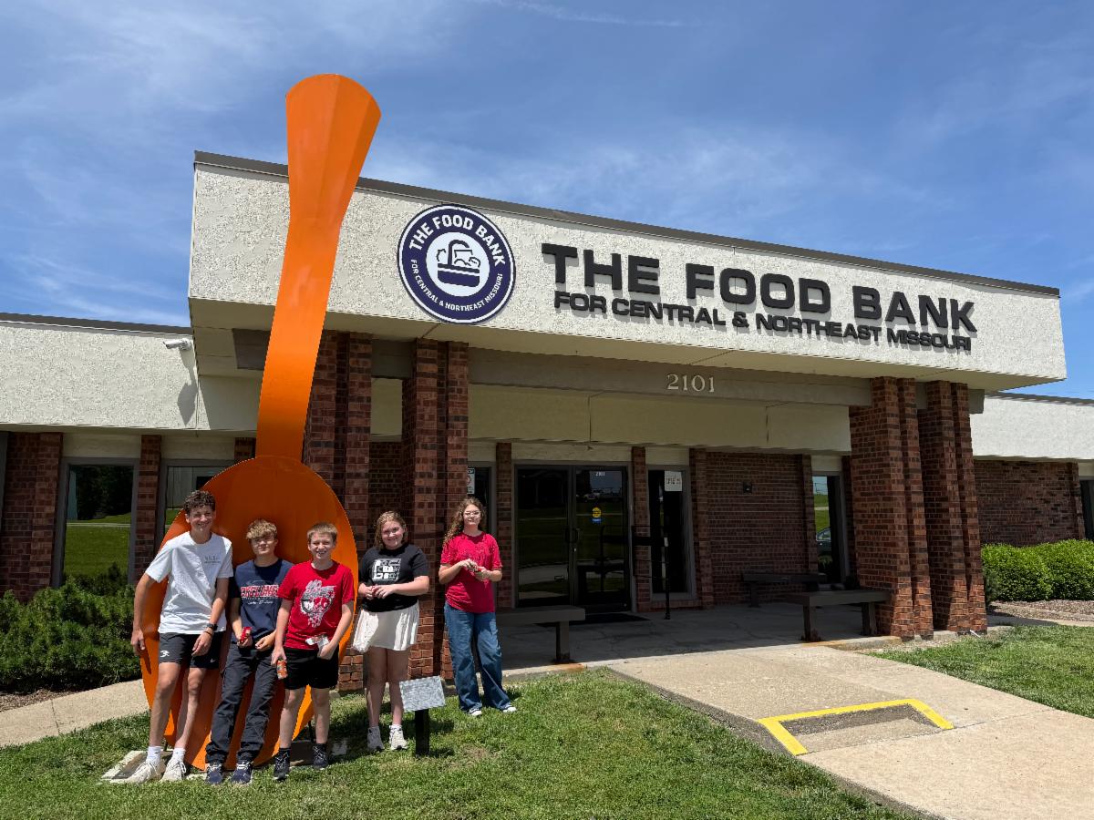 Youth In Action volunteers stand in front of the Food Bank at the big spoon. 