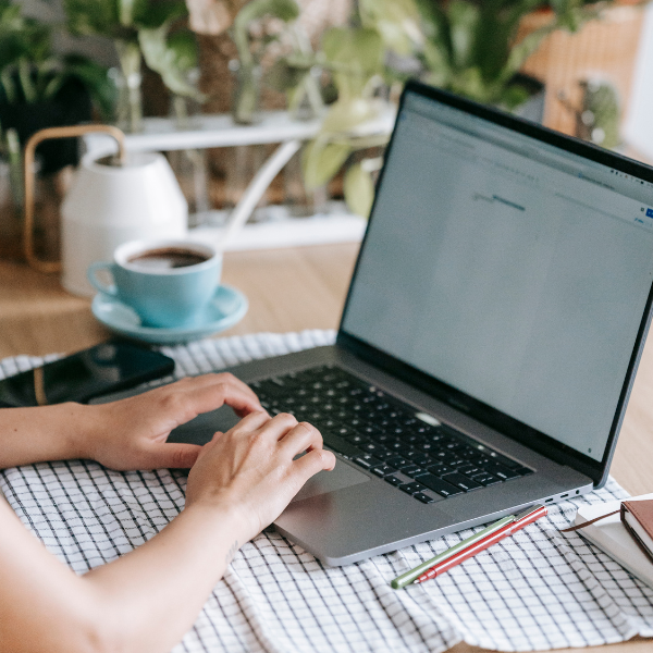 Hands at a laptop keyboard at a kitchen table
