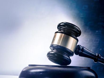 Wooden gavel with brass accent with a gradient gray background