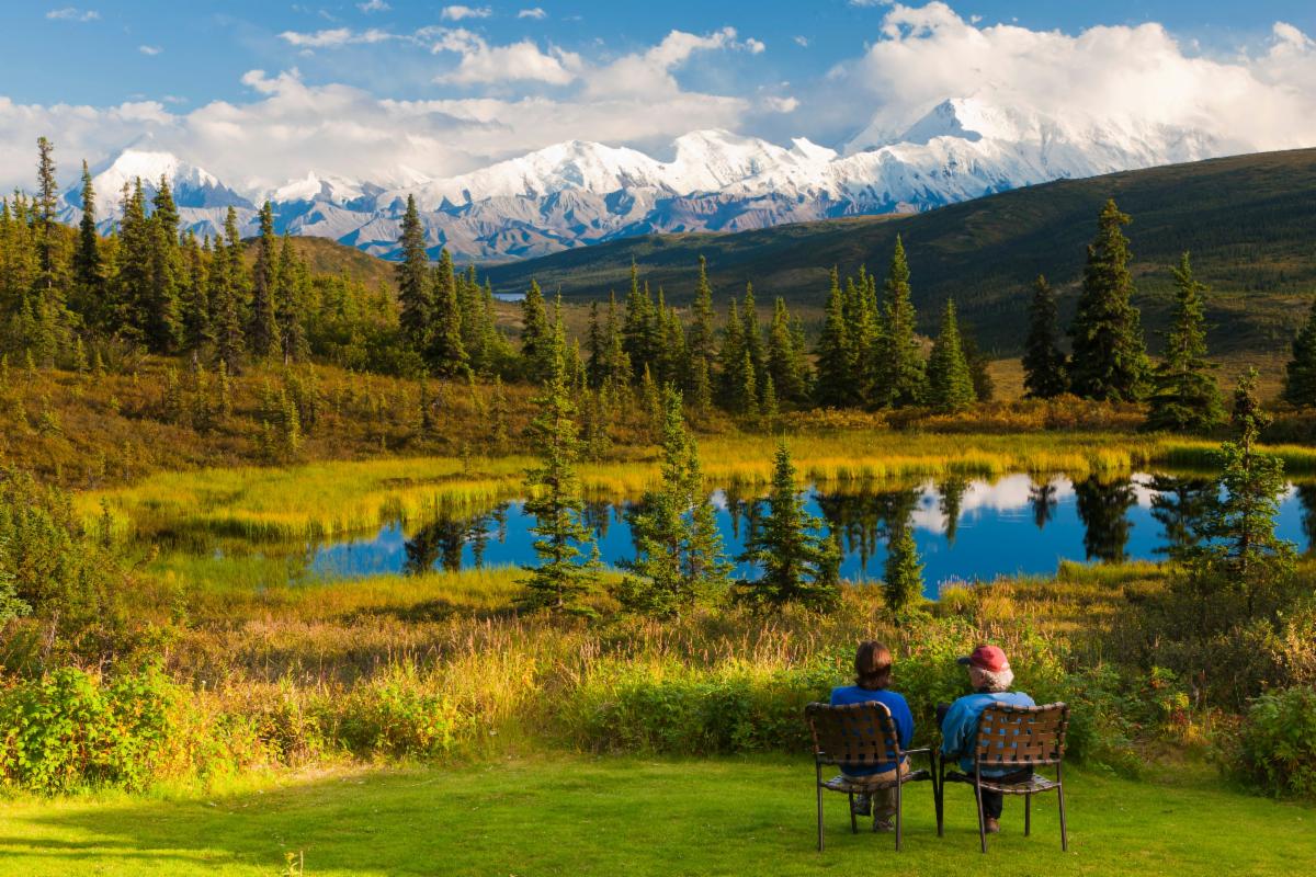 Two individuals seated on chairs, engaged in conversation or contemplation in a relaxed setting.
