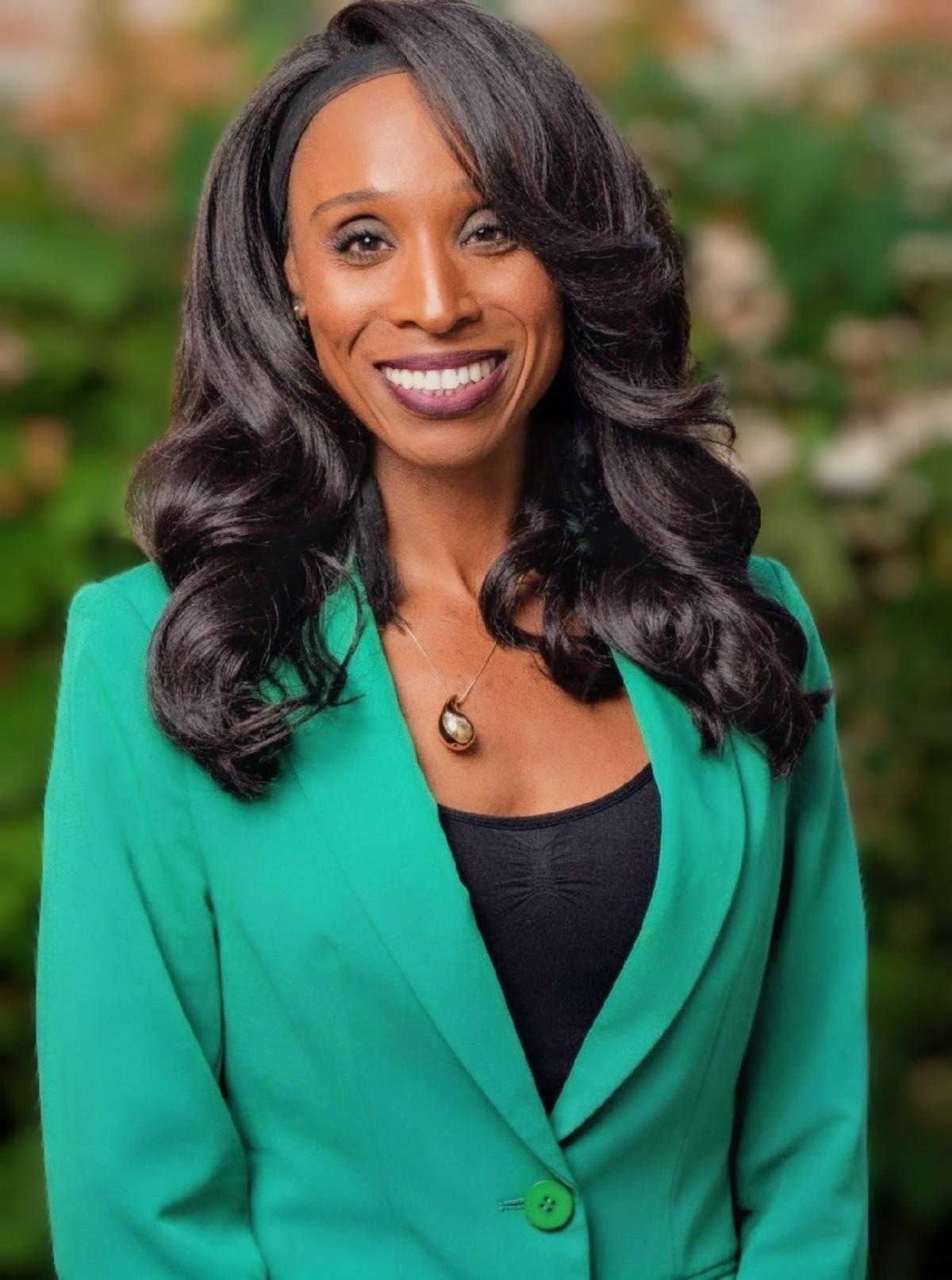 Erica Manuel smiling in green jacket and black shirt