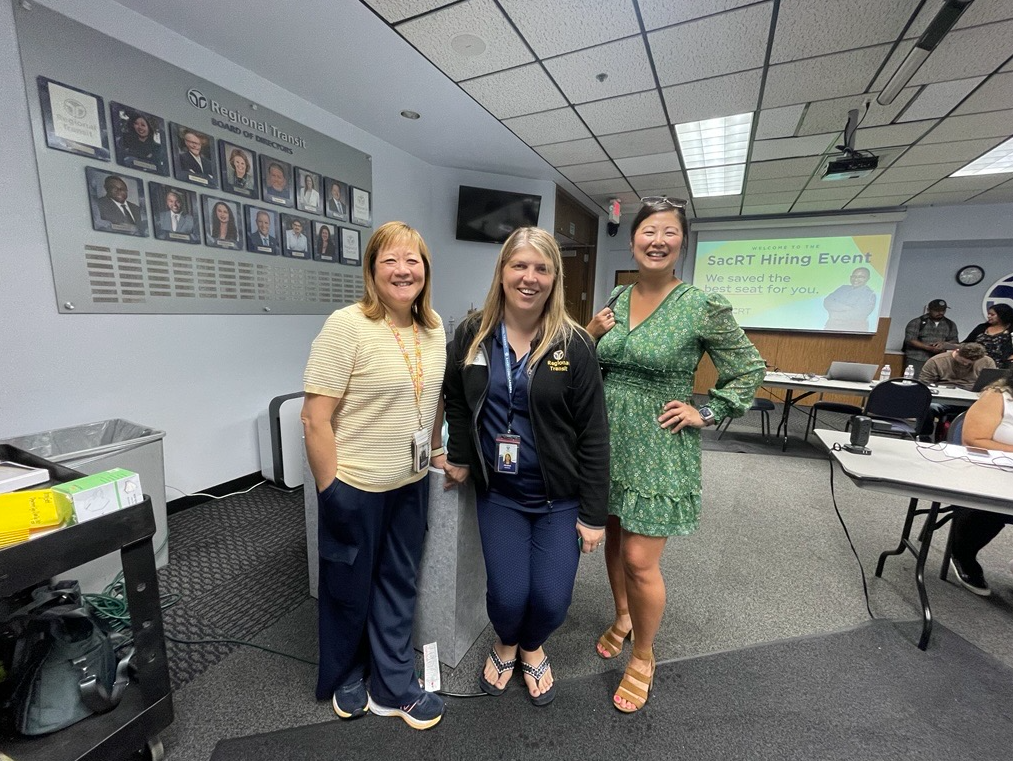 Three women standing and smiling in a classroom style room