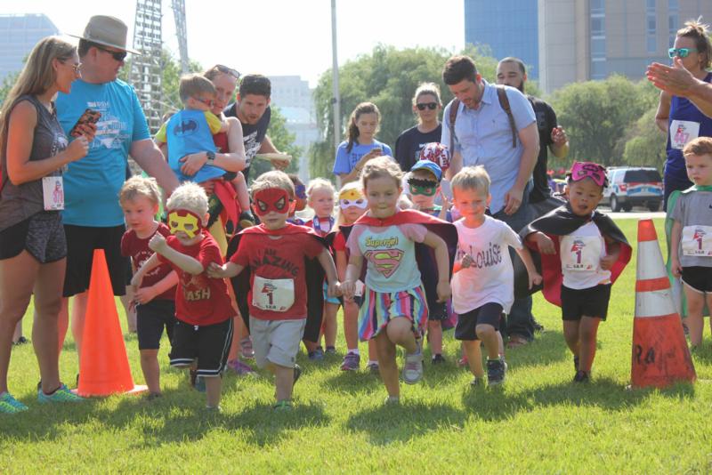 group of kids in superhero outfits running towards camera