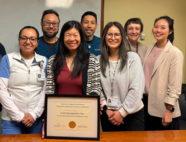 seven people pose for a photo with a framed award certificate